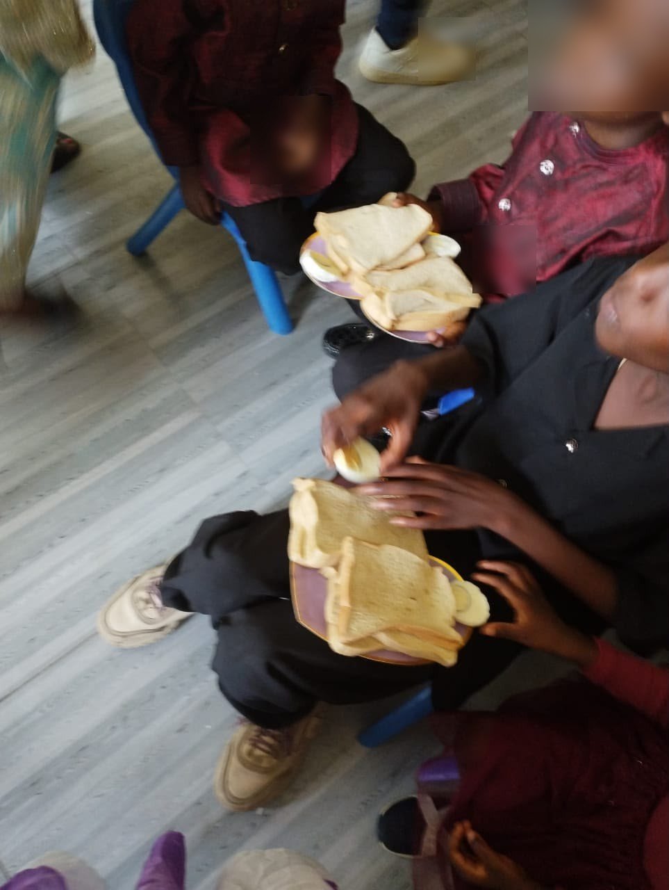 Children holding plates of bread and eggs at an HCCO feeding event