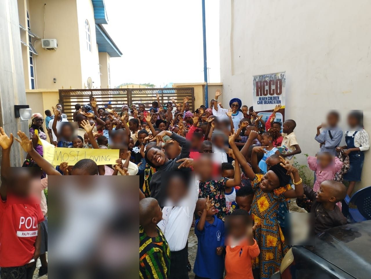 Children celebrating at an HCCO event, holding a sign reading Most Loving
